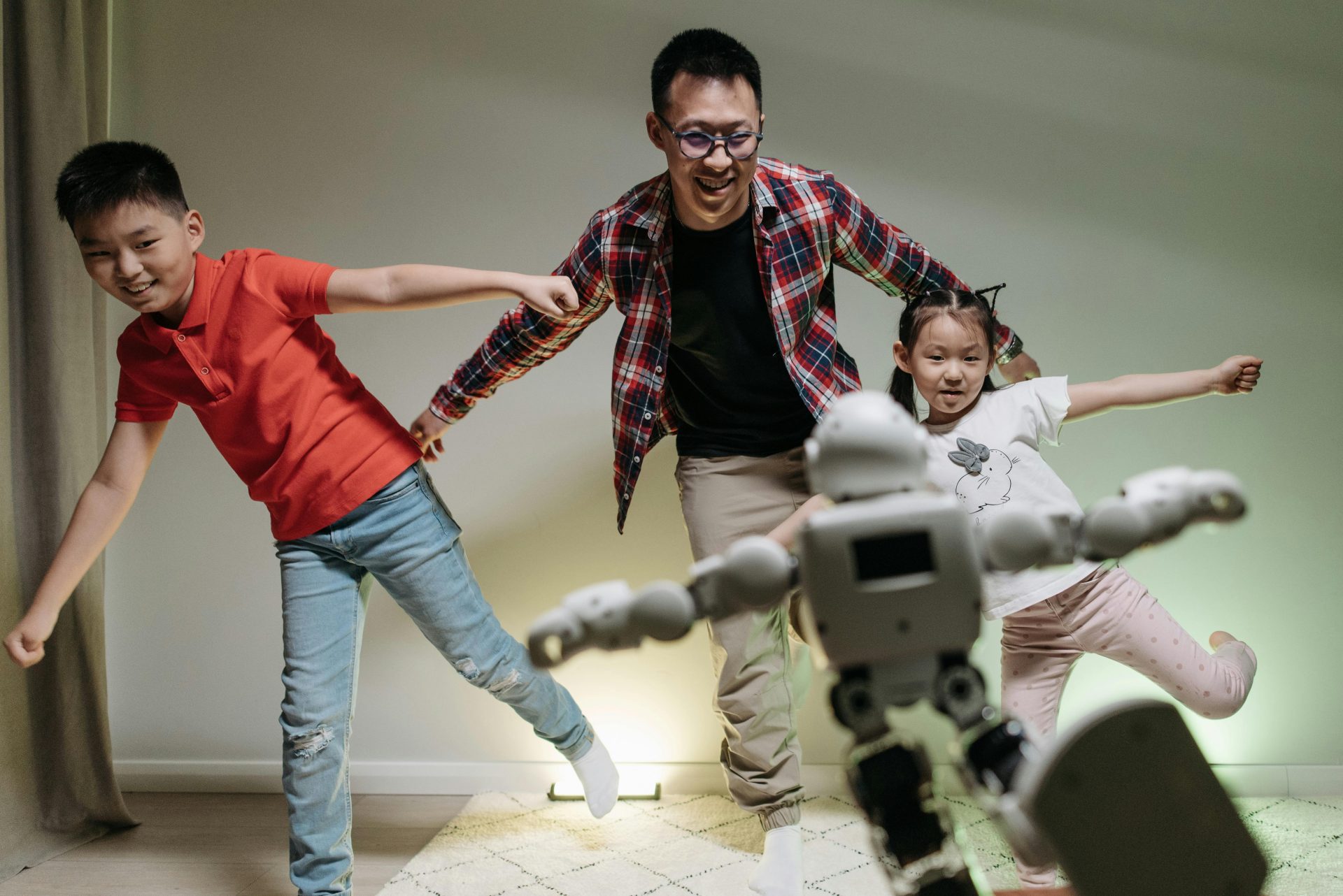 Asiatische Familie genießt die Spielzeit mit einem tanzenden Roboter und präsentiert Freude und Technologie im Innenbereich.