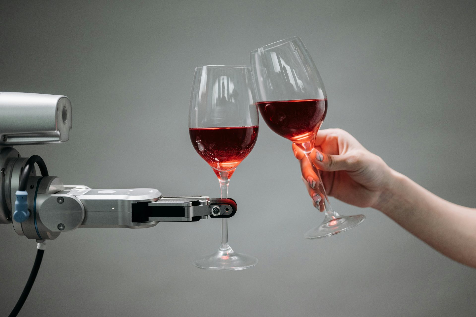 Ein Roboter und eine menschliche Hand stoßen mit Rotweingläsern an und symbolisieren Technologie und Feiern.